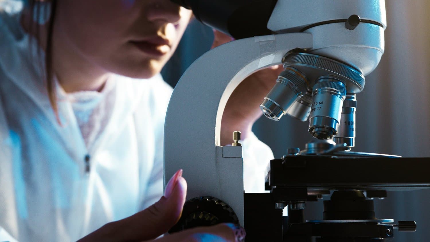 A professional looking into a microscope.